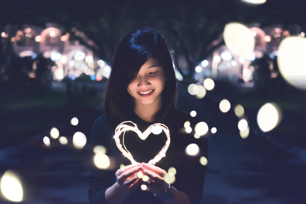 woman holding lit up heart after substance abuse treatment at Casa Capri Recovery