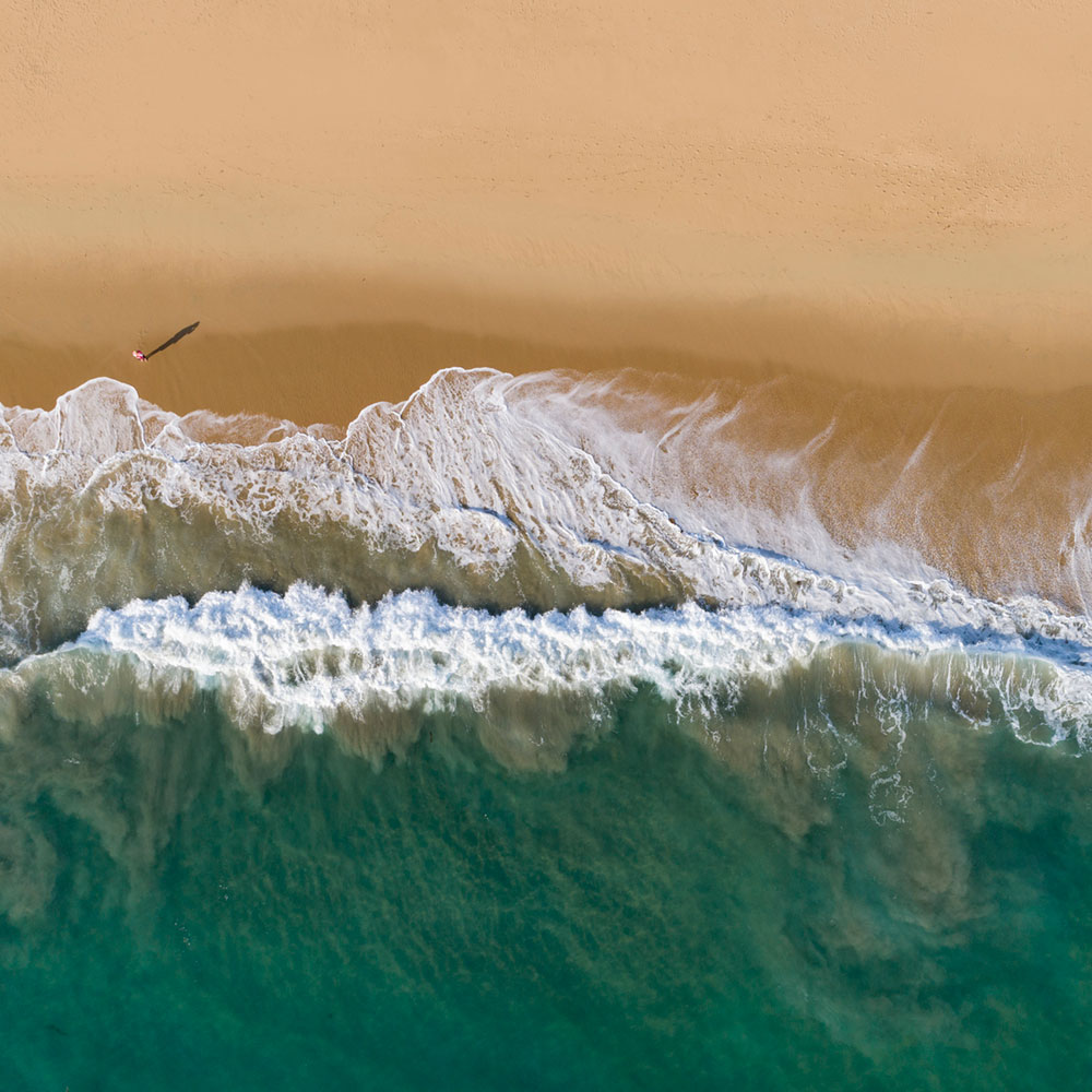 an overhead view of a beautiful beach, with a teal ocean