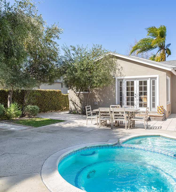 a beautiful, blue pool in a back yard surrounded by trees and greenery