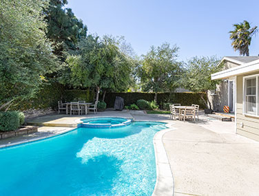 a beautiful, blue pool in a back yard surrounded by trees and greenery
