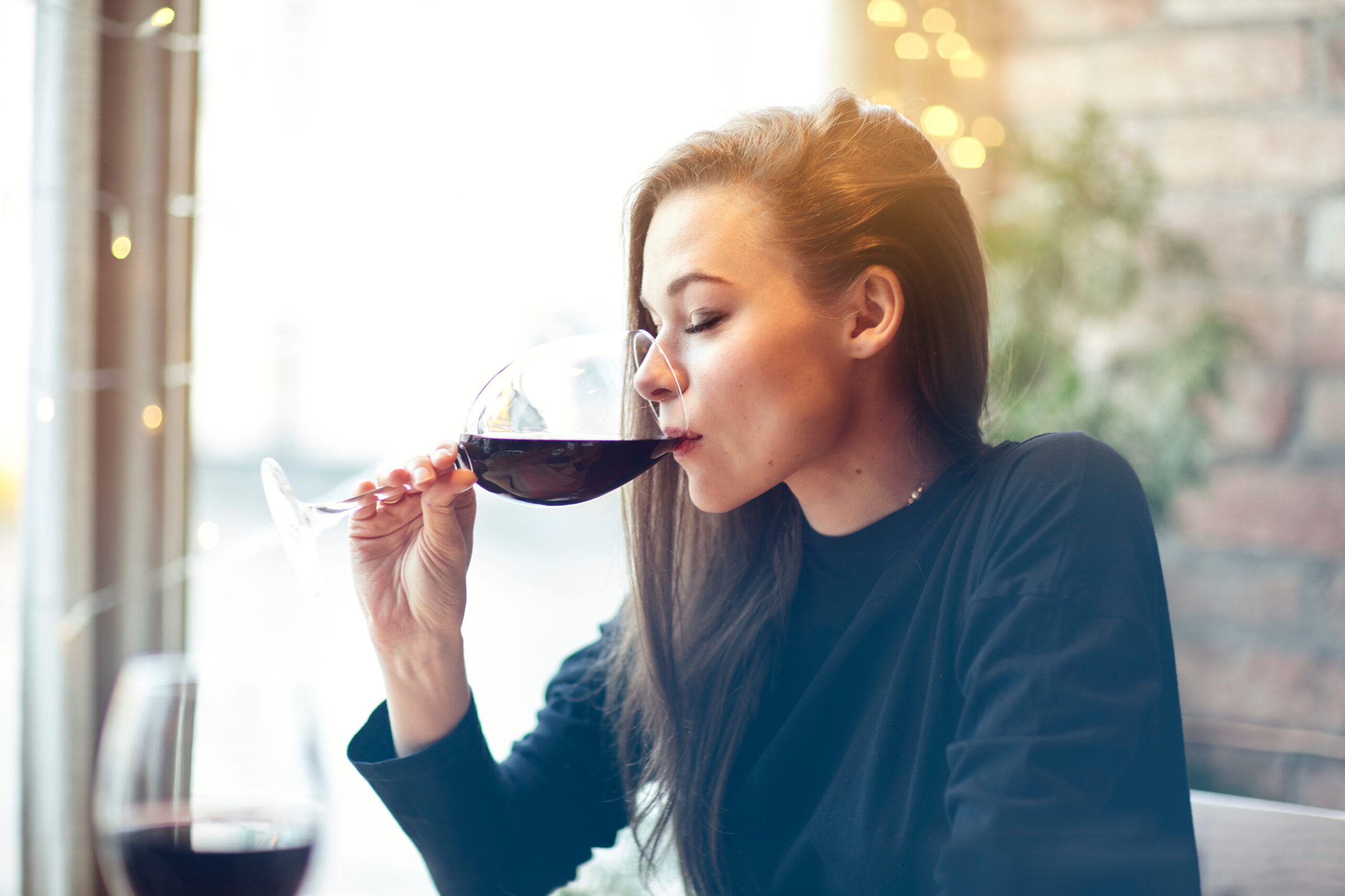 Woman drinking wine symbolizing wine mom culture.