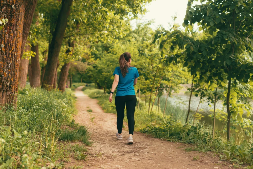 Woman walking outdoors along a path on a sunny day