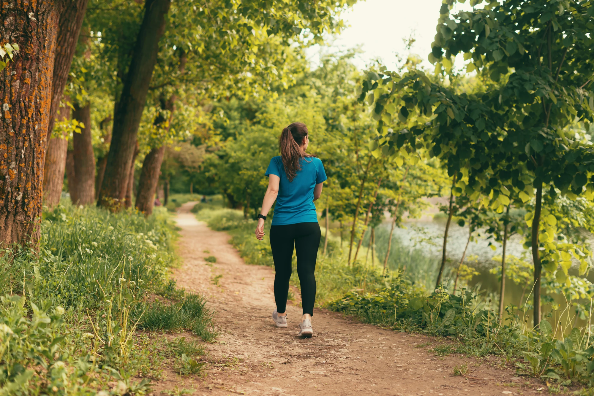 Woman walking outdoors along a path on a sunny day