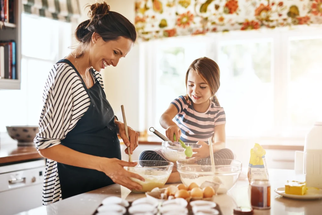 Mother and young daughter preparing food together in the kitchen
